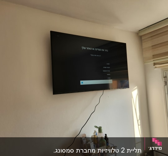 טלוויזיה תלויה על הקיר עם כבל חשמל גלוי
